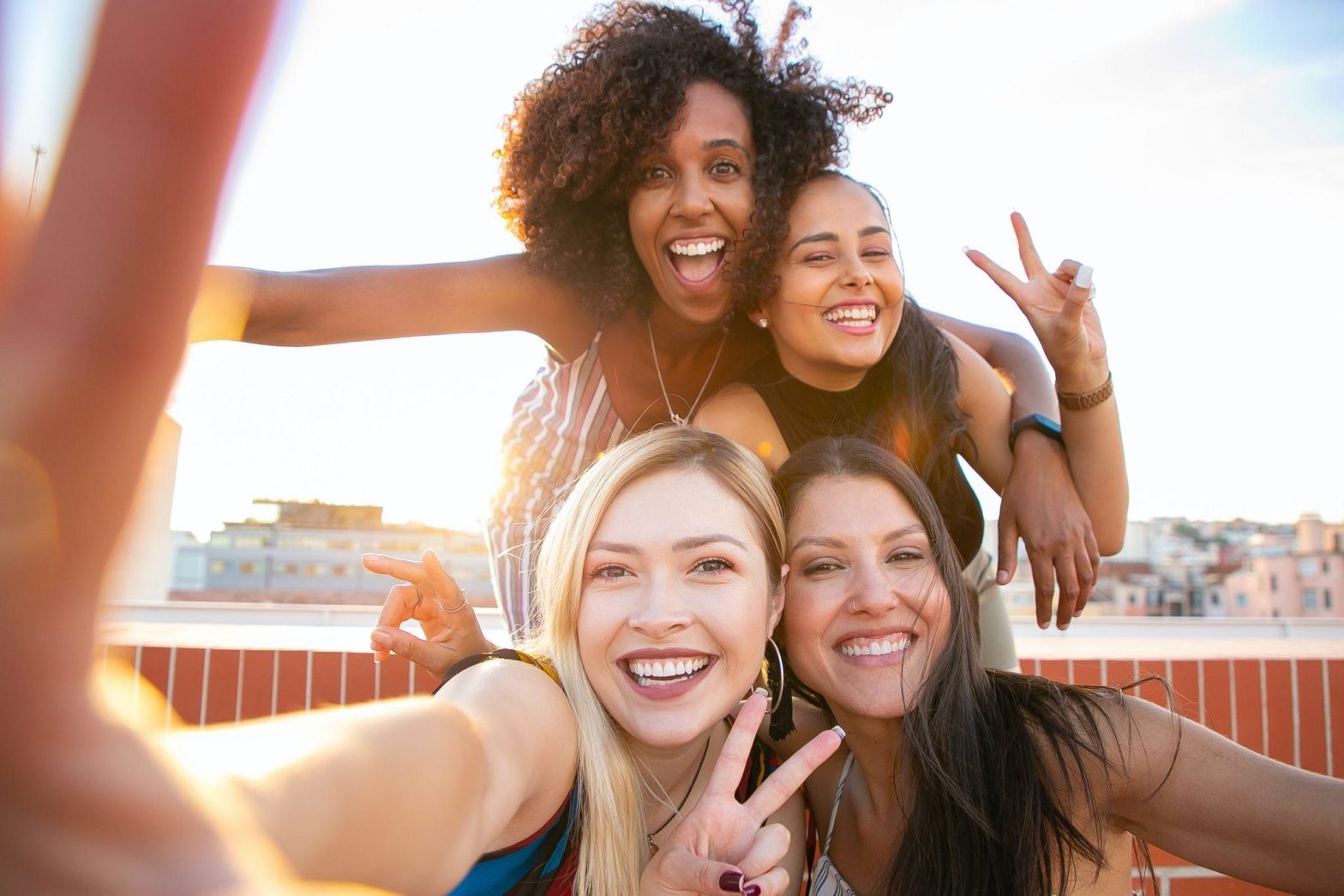 Group of 4 happy women taking a selfie on the rooftop