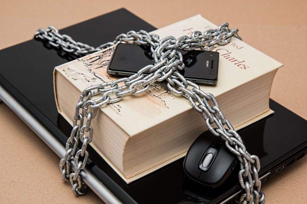 Image of smartphone, book, laptop and mouse chained up signifying social media detox